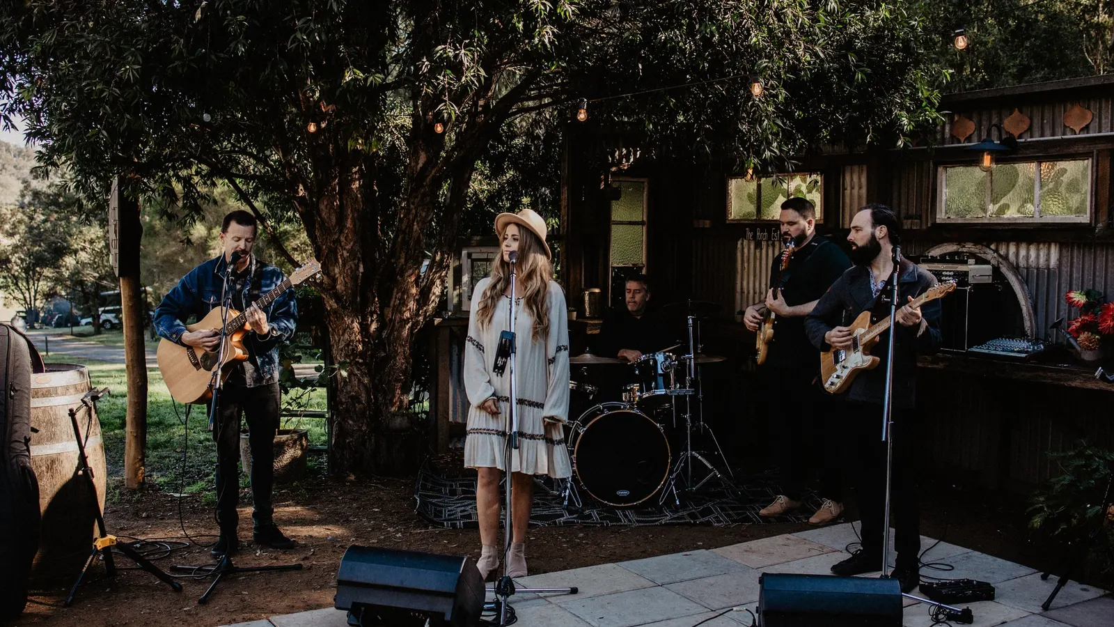 Live band performing outdoors on a stone patio under festoon lights